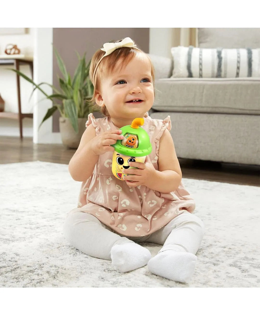 Baby sitting on a rug holding a toy in a living room