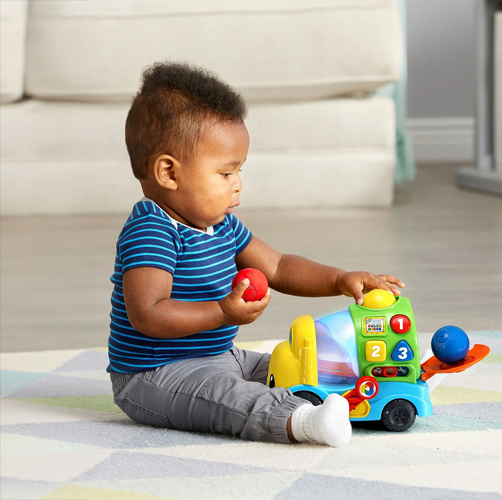 Child playing with a colorful toy on a checkered blanket